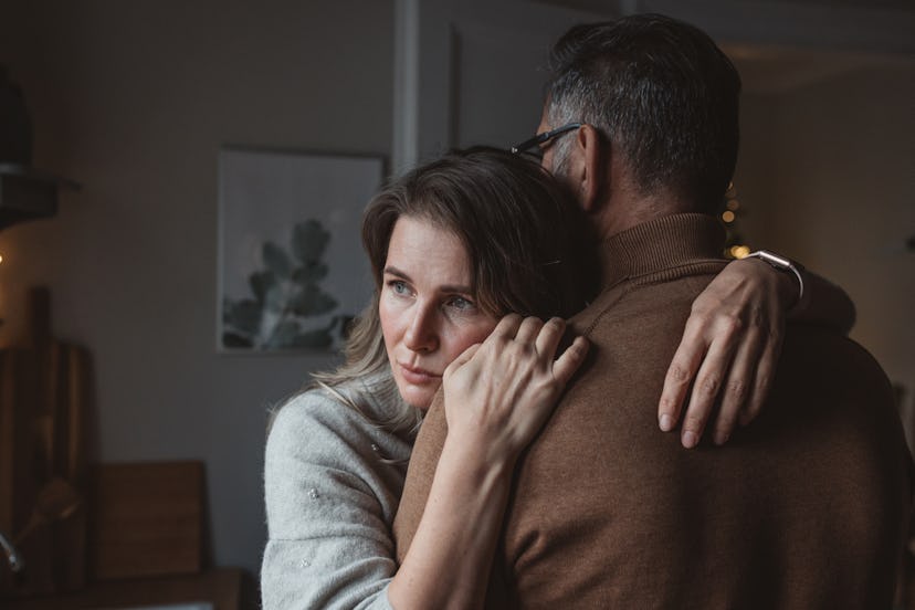 Woman hugging husband but looking away from him