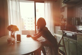 woman at her kitchen table, looking out the window
