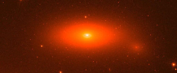 An oval-shaped galaxy, glowing in shades of red like a baleful giant eye