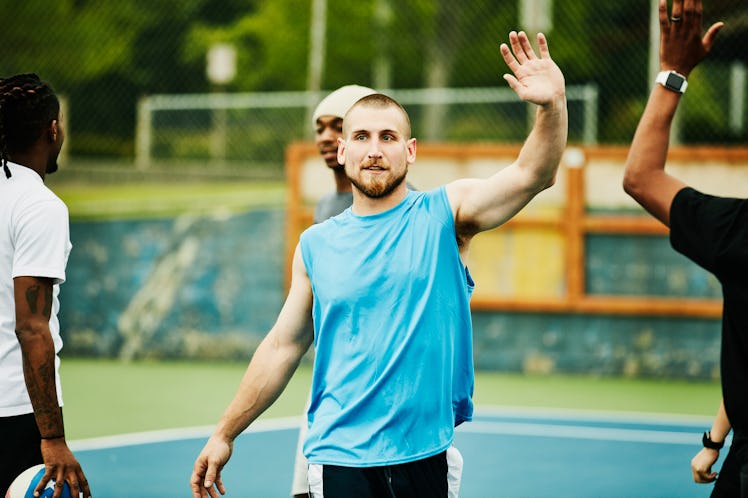 Men playing basketball outside and high-fiving.