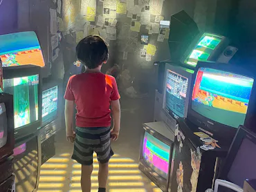 A child surrounded by old video game screens in 2023