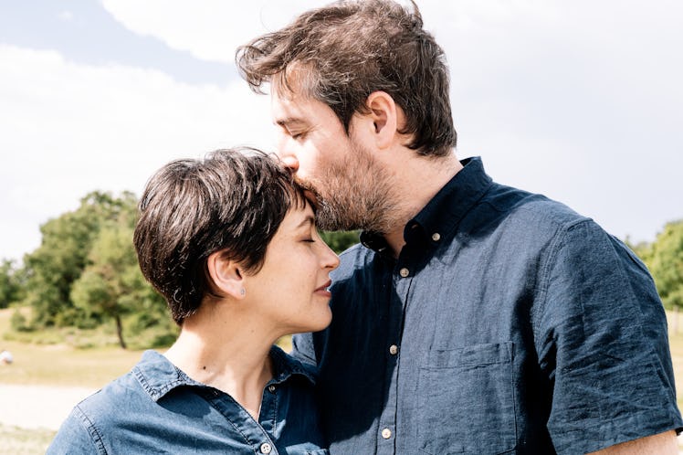 Man tenderly kissing woman on the forehead