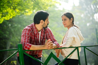 Man and woman standing on a bridge having a conversation