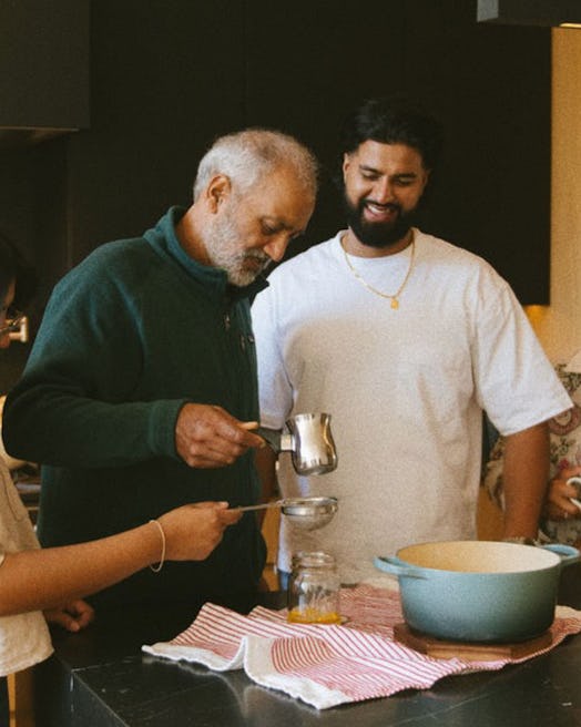Ghlee makes products by hand. Man stands, surronded by family, making ghee, the main ingredient for …