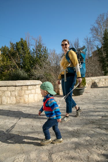 A mom walking her son a child leash.