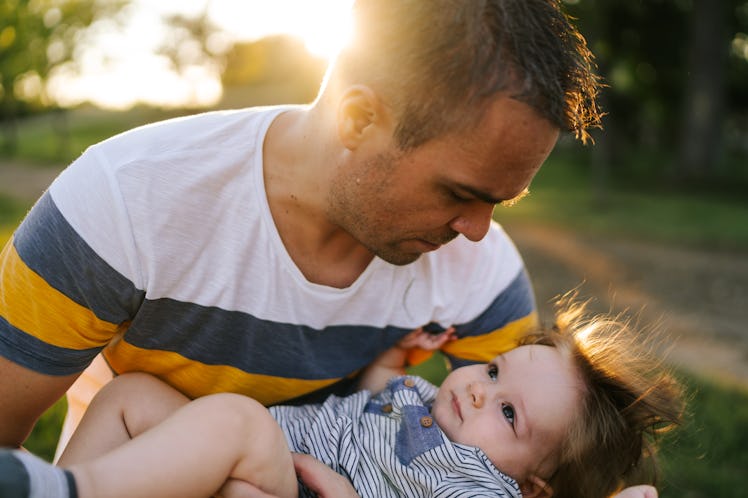 A dad holding his child in his lap outside.