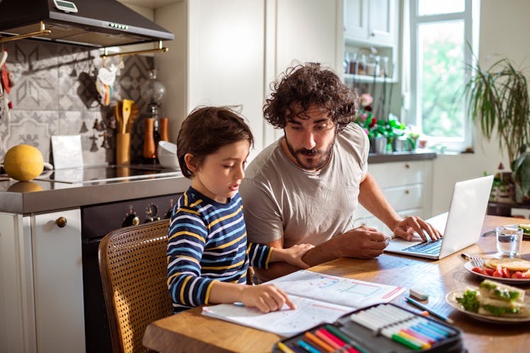 Dad and son at table doing schoolwork together