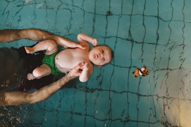 A dad in ISR swim lessons helping his baby float on their back.