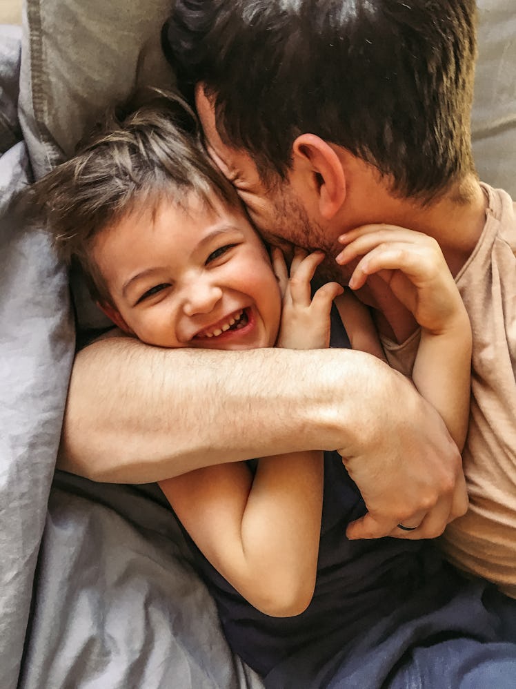 A dad and his son cuddling and smiling.