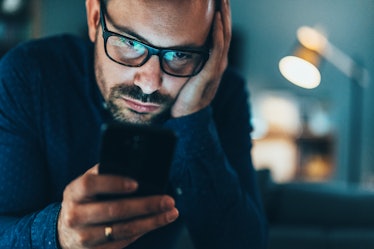 Man with glasses looking at phone about to send an important text