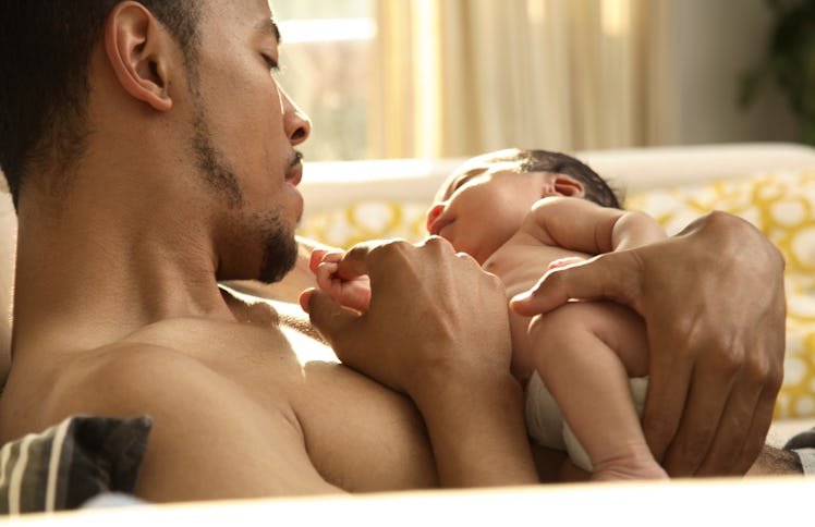 A bare-chested father holding his baby.