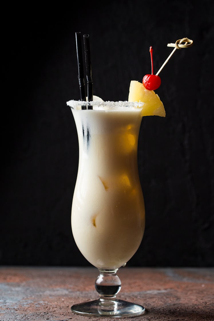 A Piña Colada in a tall glass sat on a bar