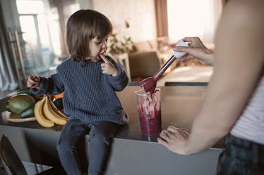 A dad and daughter making a kids' protein shake together in a kitchen.