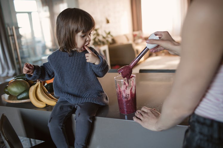 A dad and daughter making a kids' protein shake together in a kitchen.