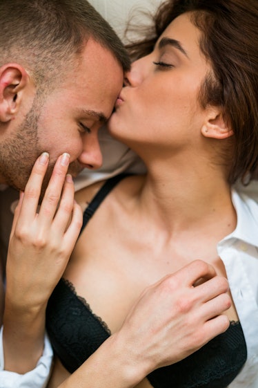 A woman kissing a man, who is looking at her boobs.
