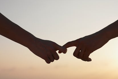 A man and woman's hands sliding away from one another's grasp