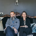 Middle aged couple sitting on a couch looking upset and towards the camera