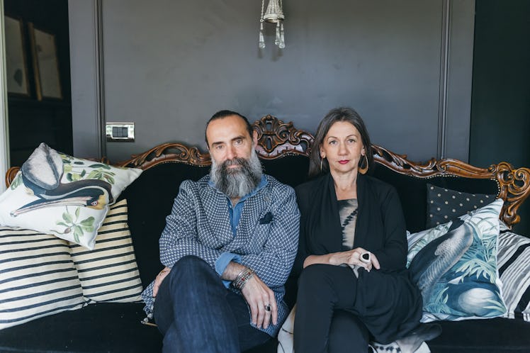Middle aged couple sitting on a couch looking upset and towards the camera