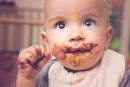 一个baby with brown smeared on their face because they ate poop.