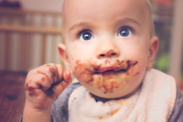 A baby with brown smeared on their face because they ate poop.