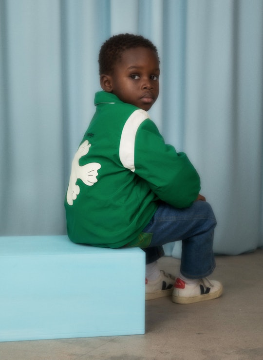 young child in a green jacket with a dove on it from the Mini Rodini x Wrangler line