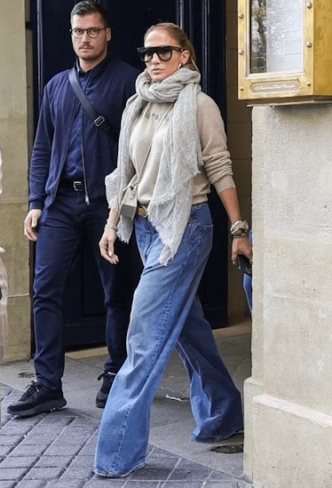 Jennifer Lopez wears baggy jeans, a crewneck sweatshirt, and scarf while in Paris, France.