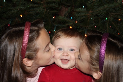 Ben smiling with two girls kissing his cheeks 