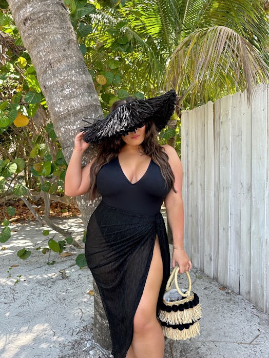 Bella Gerard wears a black swimsuit by TA3 with a plunging neckline.