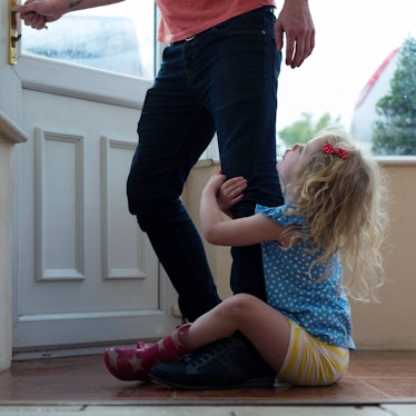 A child clings onto her father's leg as he tries to leave their home.