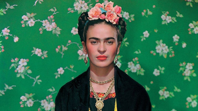 Frida Kahlo in front of a green floral background wearing a flower crown easy <a href=