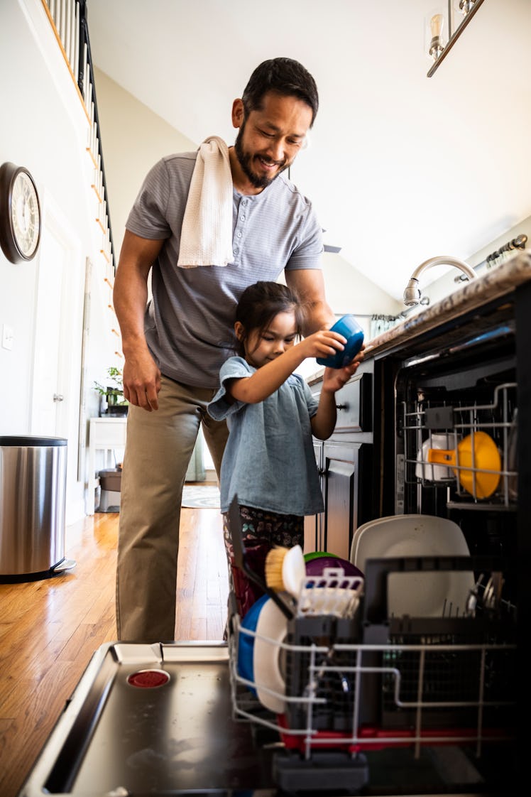 A dad helps his daughter load the dishwasher.