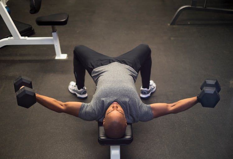 A man doing a bench press alternative on a workout bench.