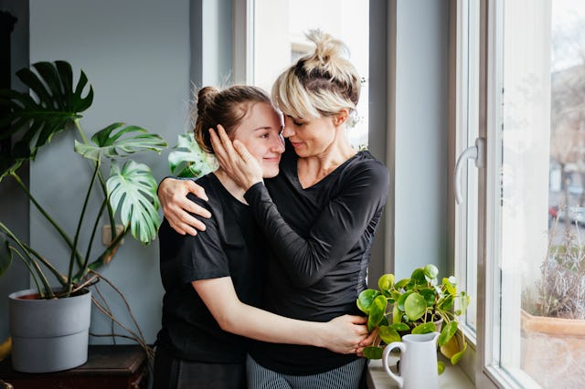 A mother hugs her teenage daughter.
