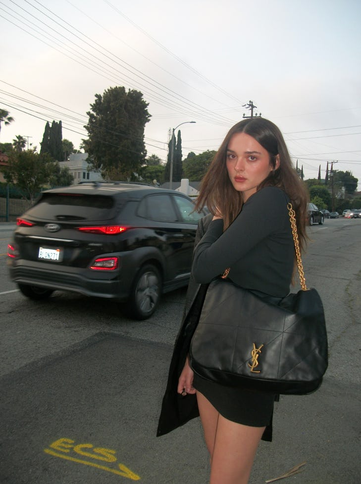 Charlotte Lawrence carries the Saint Laurent Jamie 4.3 bag in an all-black outfit.