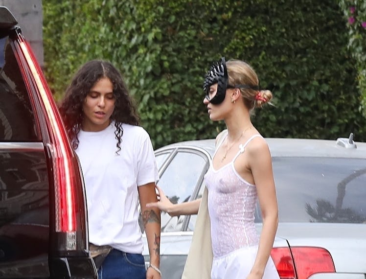 Lily-Rose Depp wears a white see-through top paired with a matching white skirt, red heels and a cat...
