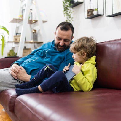 A dad and son sitting on a couch, talking.