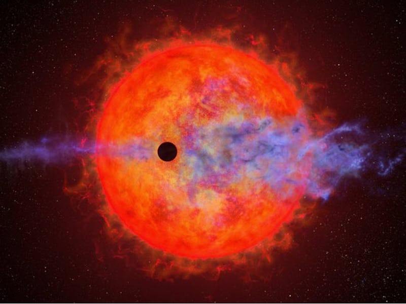 This artist's illustration shows a planet (dark silhouette) passing in front of the red dwarf star A...