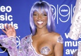 Lil' Kim wears a one-sided jumpsuit and a nipple pastie at the 1999 VMAs.