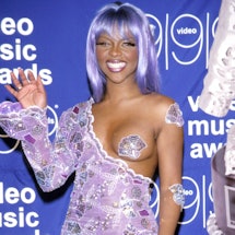 Lil' Kim wears a one-sided jumpsuit and a nipple pastie at the 1999 VMAs.
