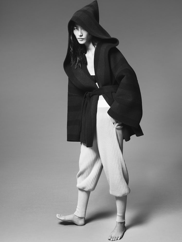 Model Liu Wen wears a black and gray wool coat and white ribbed jogger pants; black bralette.