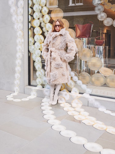 Designer Stella McCartney wears a cream fur coat, sunglasses and  white shoes.