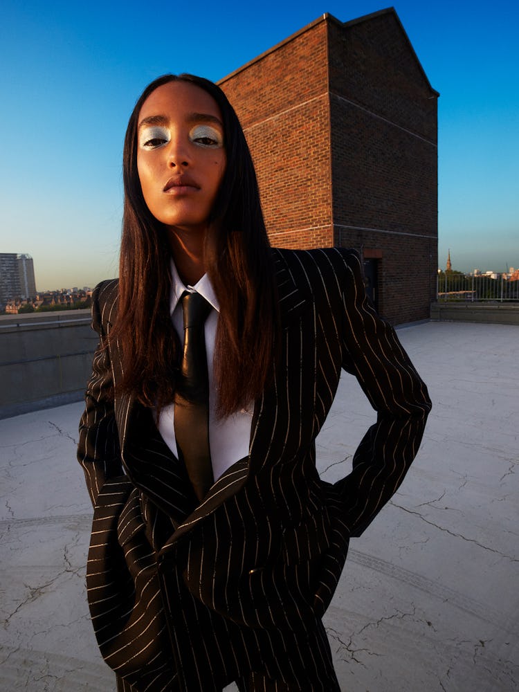 Model Mona Tougaard wears a black pinstripe suit; white button down shirt and black tie.
