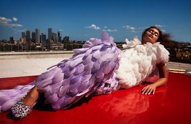 Model Gerber wears a white feather top, violet feather pants, and colorful shoes.