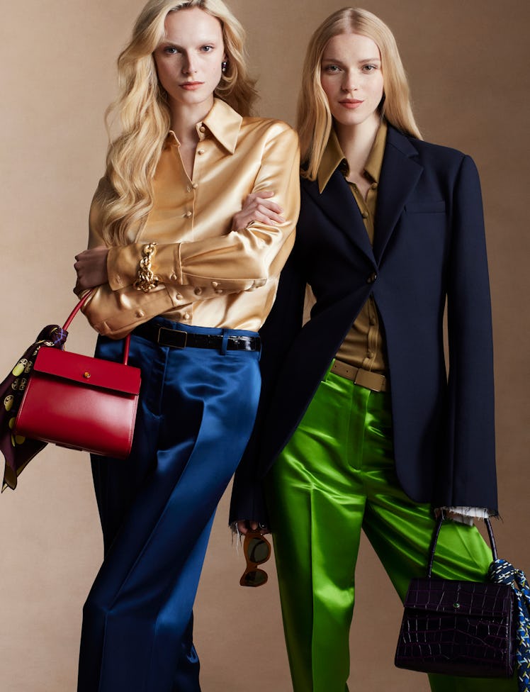 Models Alex Consani and Colin Jones wears blue silk pants, red leather handbag, gold bracelet and ye...