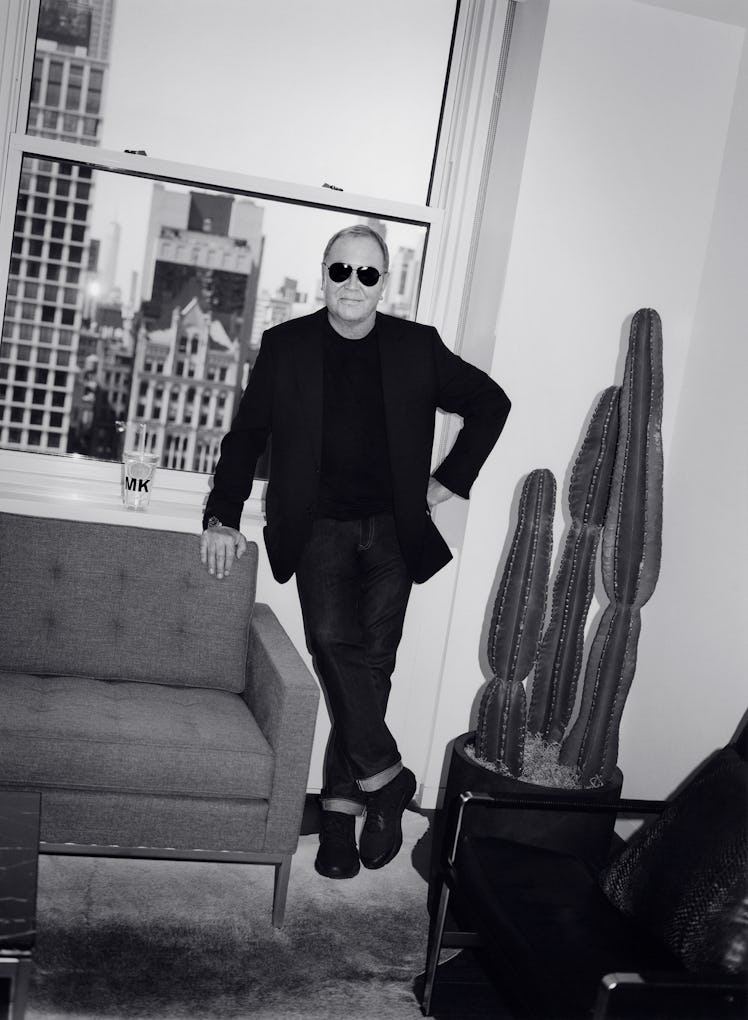 Designer Michael Kors wears a black shirt, sunglasses, black blazer, and denim jeans.