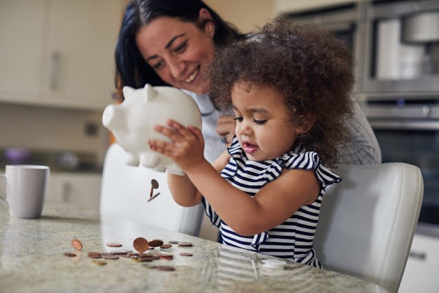 A mother helps her child empty a piggy bank.