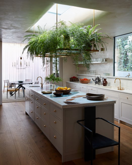 a kitchen with a terrazzo island and hanging plants