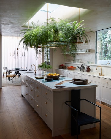 a kitchen with a terrazzo island and hanging plants