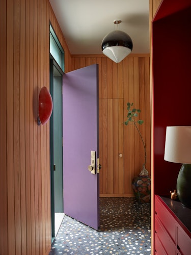 An entryway with a purple door designed by Studio Shamshiri. 