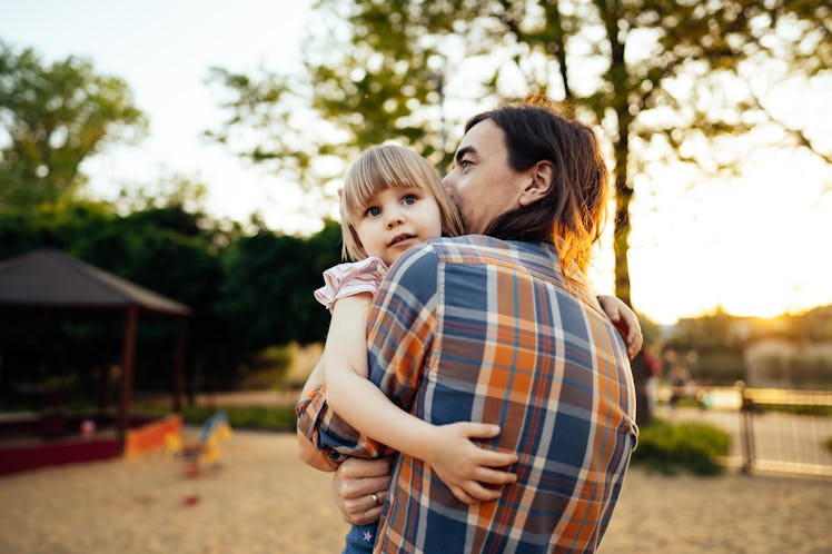 Father in plaid shirt holding young daughter in his arms